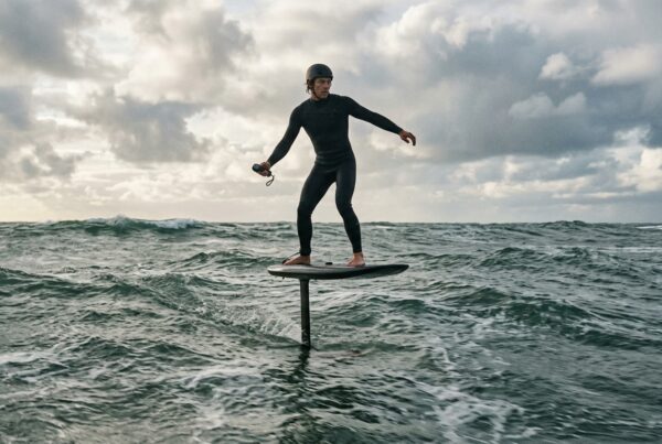 Rider en vol sur un eFoil au-dessus de l'eau grise de l'Atlantique, seul le mât perce la surface